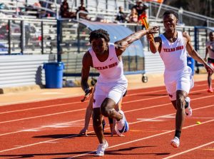 Sophomore Roman Wyatt passes the baton to his teammate during a relay race. Wyatt is recognized as an outstanding athlete by his coaches. 