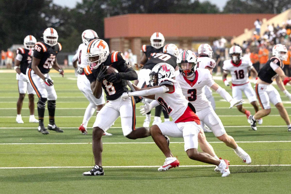 After catching a pass from senior quarterback David J Potter, junior Shavante Montgomery break a tackle in the first quarter of the varsity football game against Tyler Legacy High School on Aug. 28, 2024. Montgomery scored on the play and the Tigers defeated the Red Raiders 37-13 in the 2024 season opener at Tiger Stadium. 