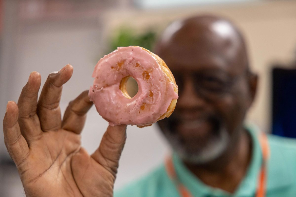 After selecting his favorite doughnut from the box in the teacher's workroom, Texas High teacher Carl Bandy examines the pink glaze before he eats his sweet treat on the "Hocus Pocus" treat day.