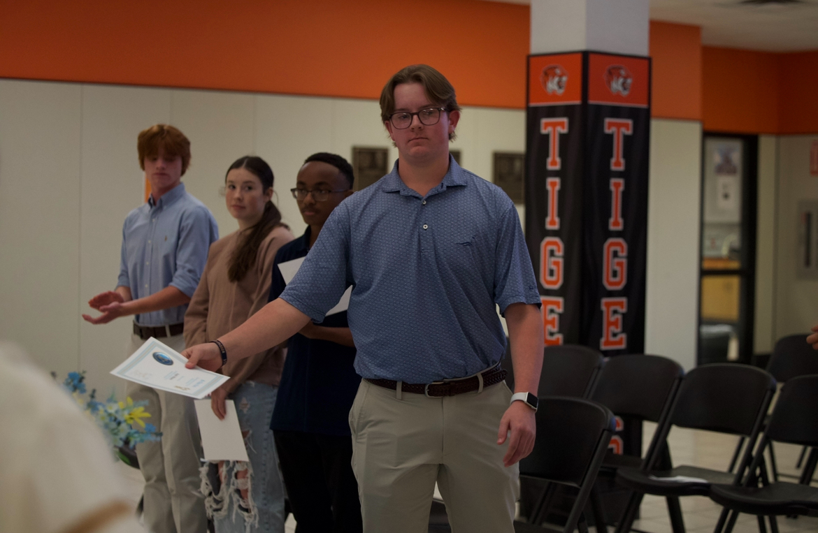 Senior Austin Williams walks up to the table as he receives his certificate of induction. The Mu Alpha Theta induction ceremony took place on Oct. 17, 2024 in the Math and Science Building.