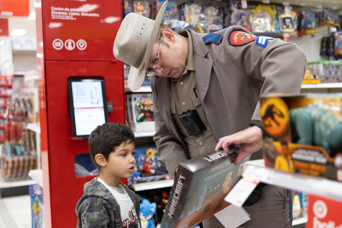 A Texas Department of Public Safety Trooper examins a Minecraft toy with his shopper at the Shop with a Cop & Firefighter event on Dec. 3, 2024. Each child received $150 to spend at Target.