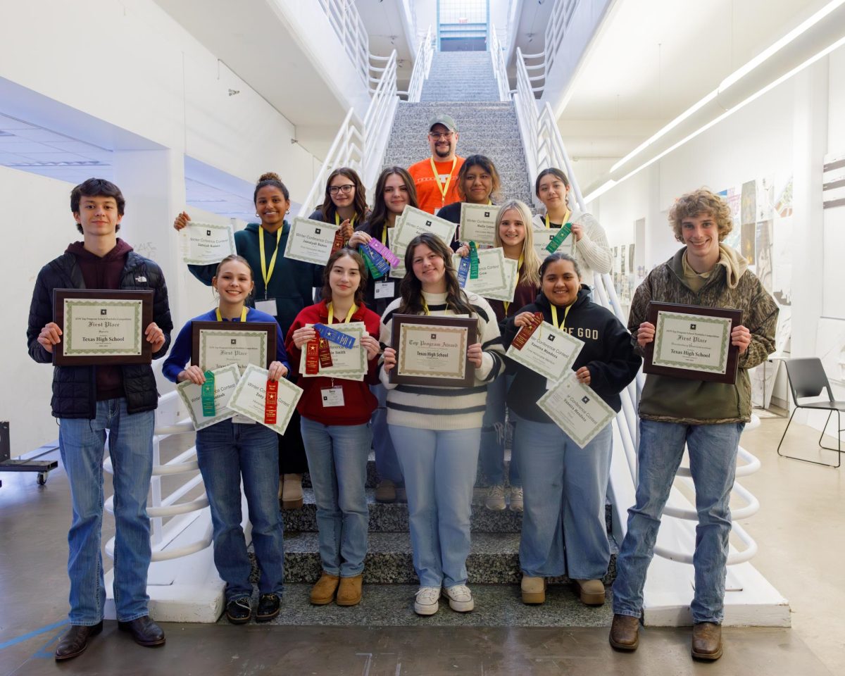 Standing together in a group, the Texas High photography staff smiles as they hold up the awards they won at the 2025 Association of Texas Photography Instructors Winter Conference in Arlington. The photographers were entered into both individual and group categories, sweeping the Beginning Portfolio and Advanced Art Portfolio competitions.